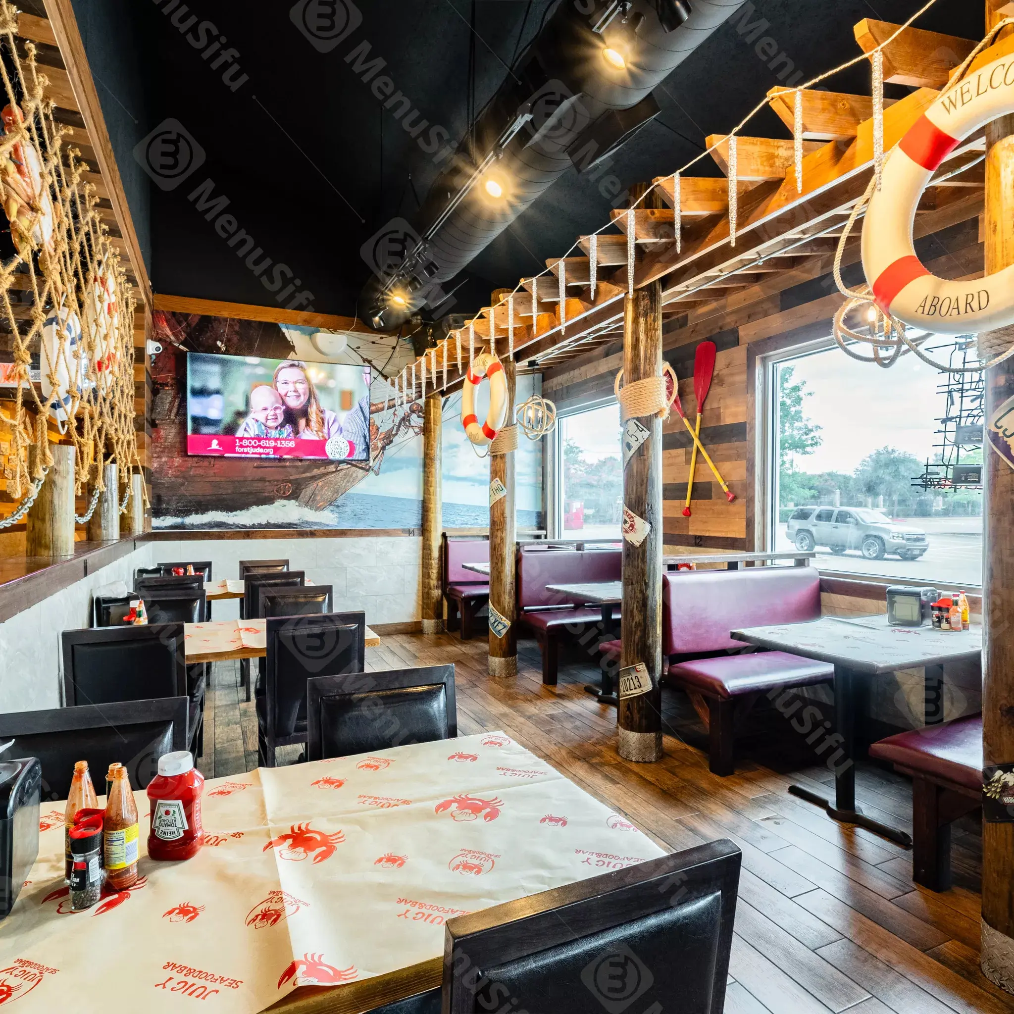 Nautical-themed restaurant interior with boat mural and life rings at Juicy Seafood And Bar, a Seafood Restaurant in TX