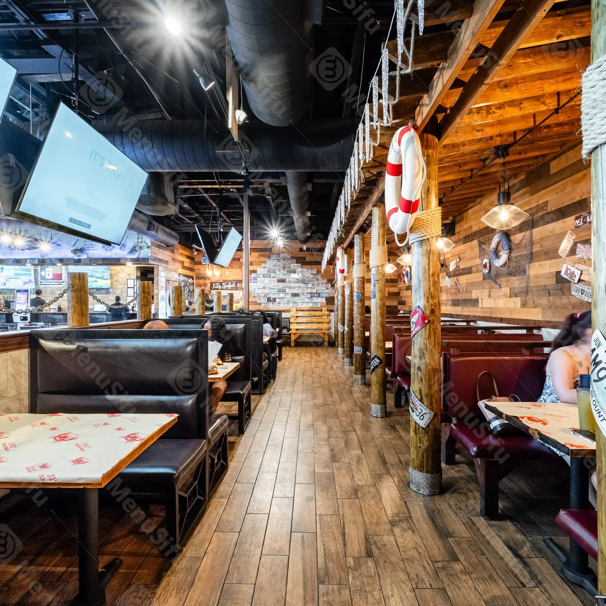 Nautical-themed restaurant interior with wooden beams and life rings at Juicy Seafood And Bar, a Seafood Restaurant in TX