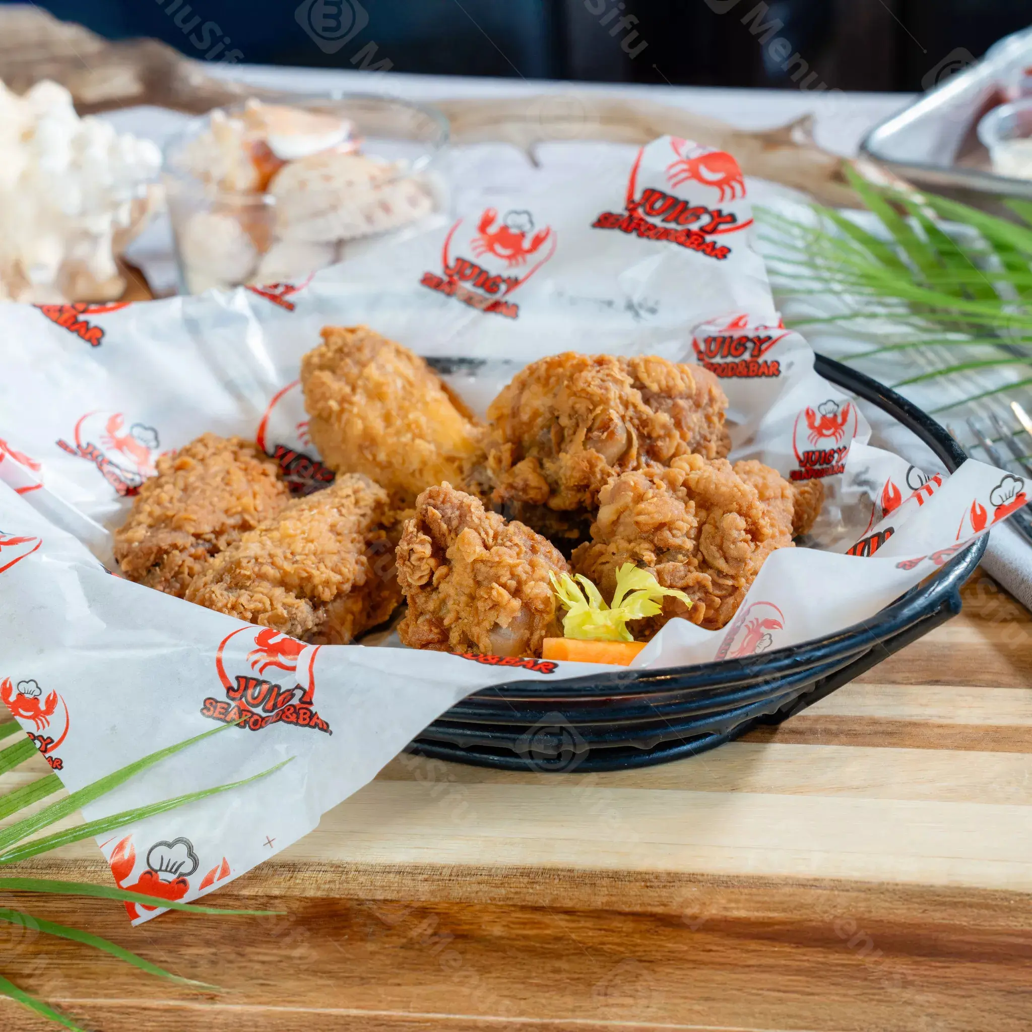 Crispy fried chicken pieces served in branded paper at Juicy Seafood And Bar, a Seafood Restaurant in TX